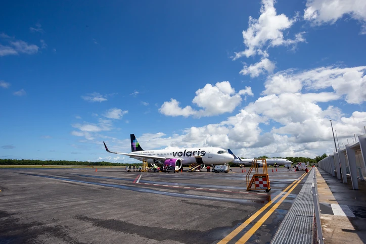 Avión de Volaris en pista, con el logo y el mensaje "100 aviones para que más personas viajen bien".