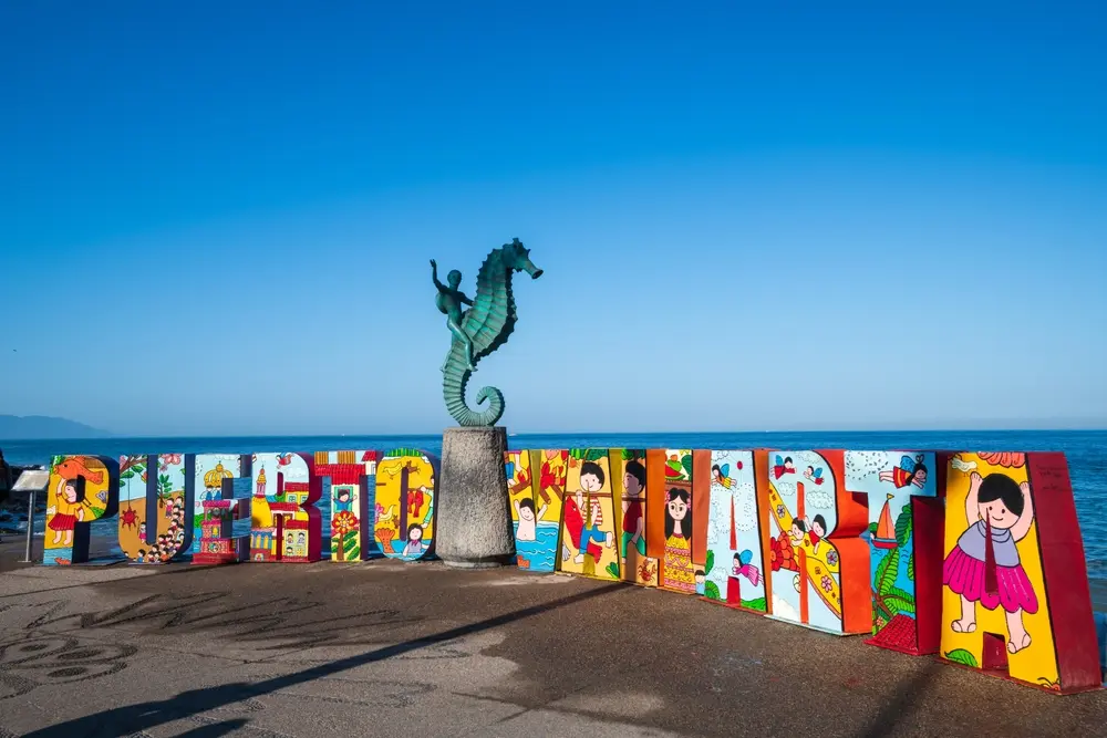Colorido cartel de Puerto Vallarta y escultura de caballo de mar en el Malecón