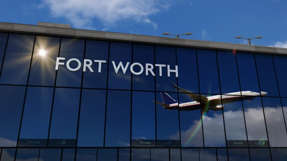 Exterior facade of Dallas Fort Worth Airport, with mirror windowpanes reflecting a plane in the sky.