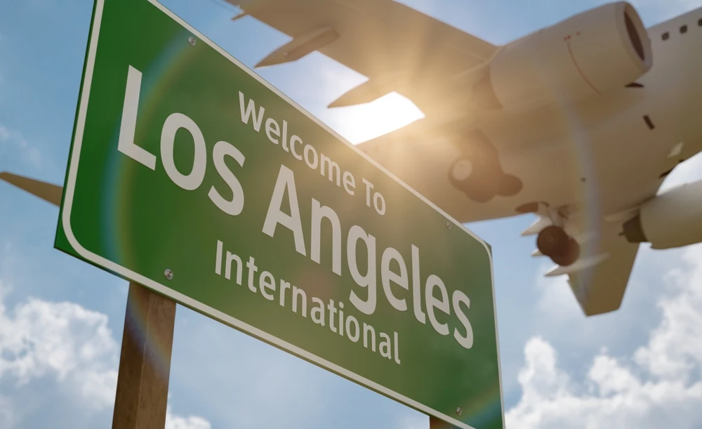 Cartel de bienvenida en el Aeropuerto de Los Ángeles con un avión sobrevolando el cielo de fondo. 
