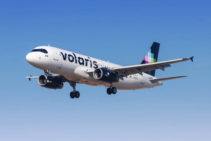 Avión de Volaris sobrevolando un cielo azul en proceso de aterrizaje.