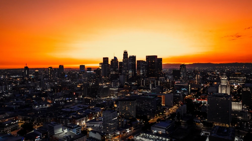 Vista aérea de la ciudad de Los Ángeles con un cielo anaranjado en el atardecer.