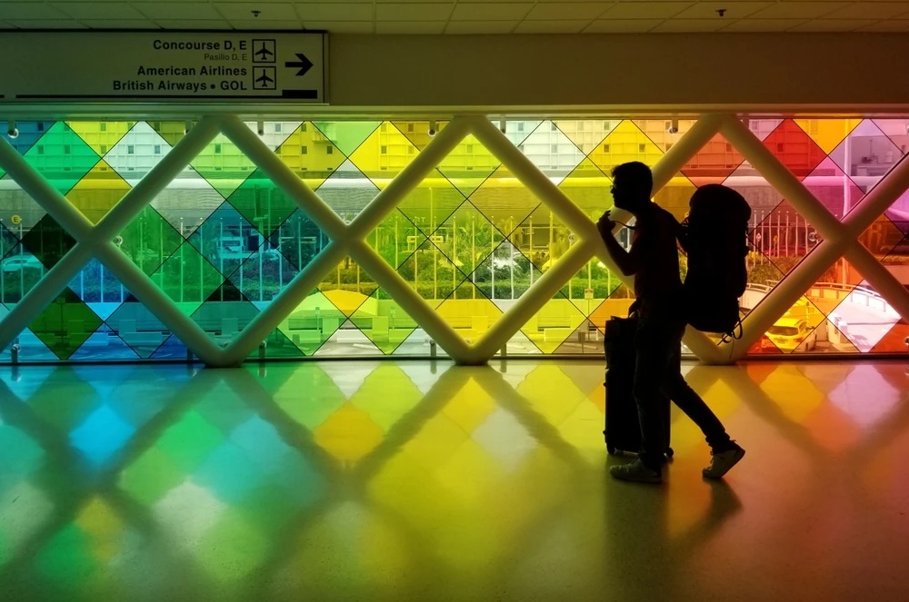 A passenger with travel backpacks walking along MIA airport.