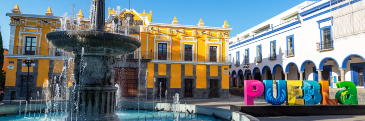 Centro histórico de Puebla, con colorido letrero de la ciudad y una fuente de agua