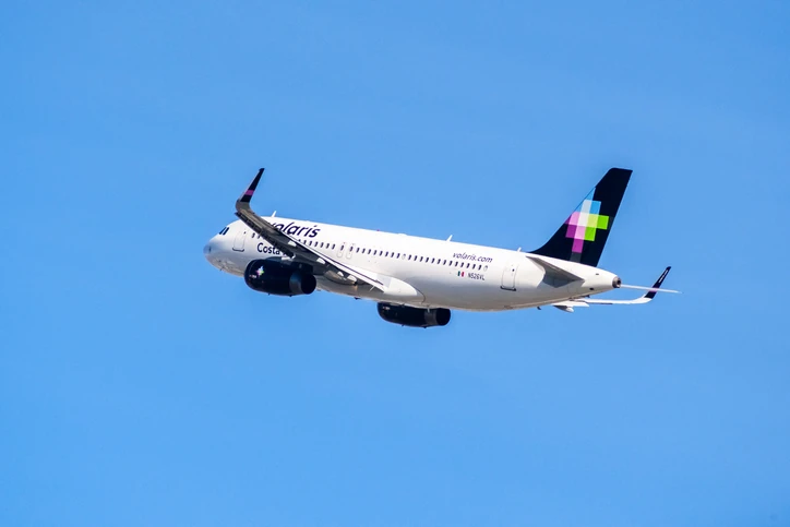 Avión de Volaris en pista, con el logo y el mensaje "100 aviones para que más personas viajen bien".