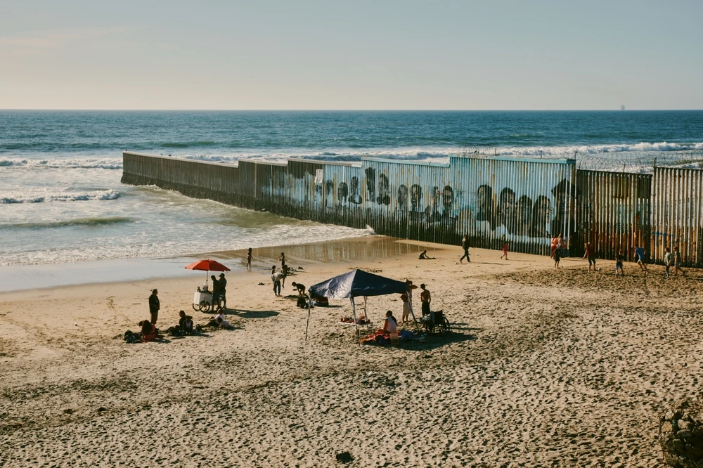 People enjoy the beach near the border wall at Playas de Tijuana.