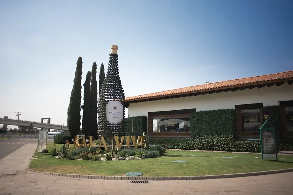 SALA VIVE winery storefront with a bottle-shaped wine display, tall cypress trees, and a sunny manicured lawn.