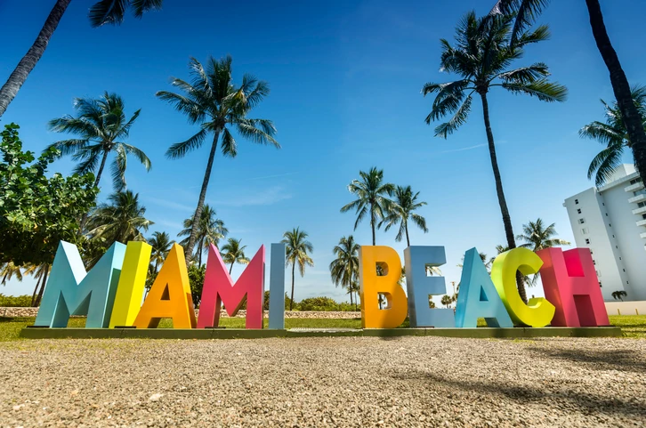 Colorful sign of Miami Beach with palm trees in the background.