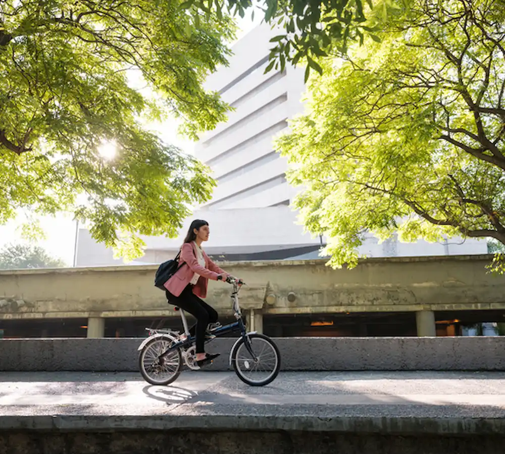 Mujer jóven en bicicleta por la Macroplaza de Monterrey.