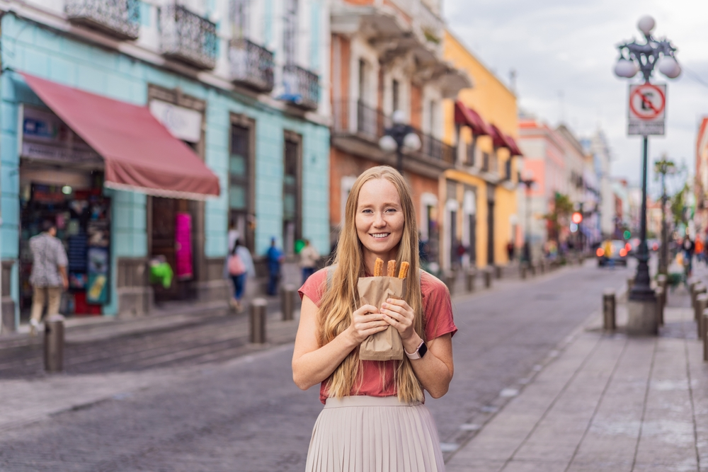 Mujer turista disfruta de una merienda en el centro histórico de Puebla, México