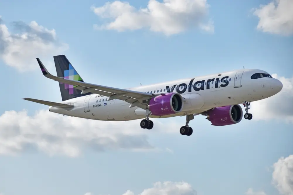 Avión de Volaris sobrevolando un cielo azul con nubes