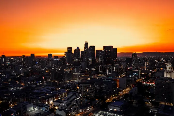 Vista aérea de la ciudad de Los Angeles con el cielo anaranjado del atardecer.