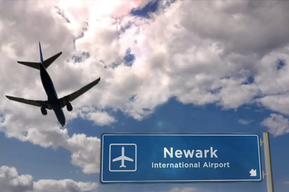 Avión volando sobre el letrero del aeropuerto de Newark