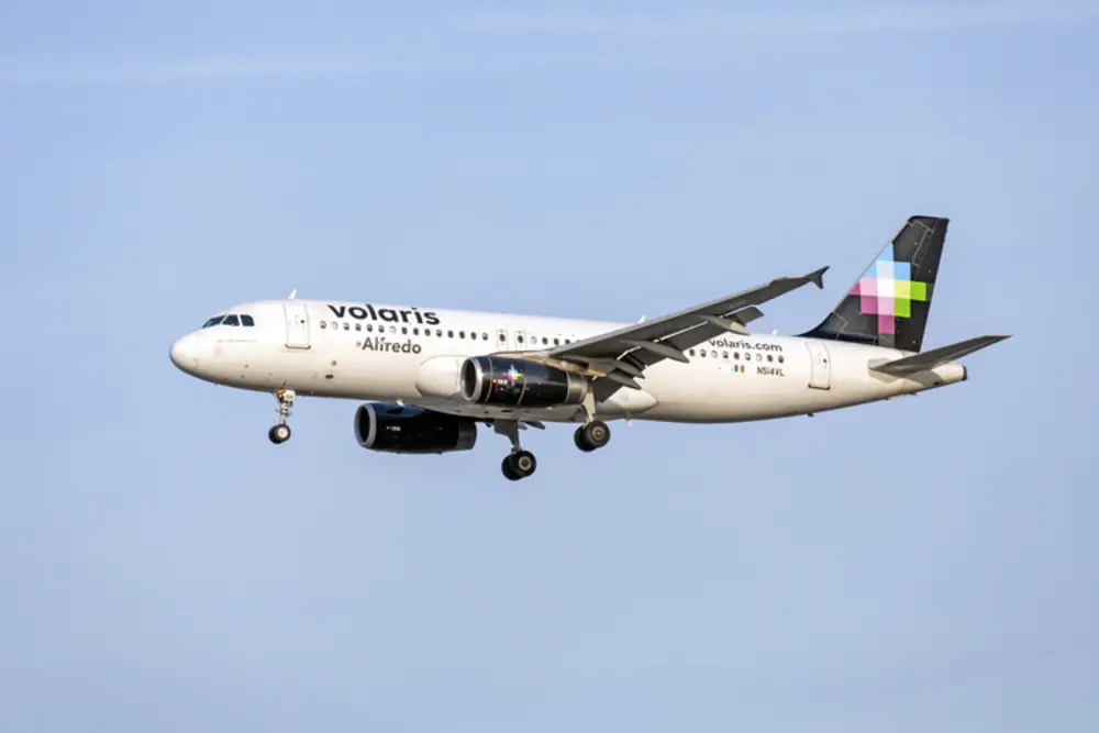 Avión de Volaris volando bajo un cielo azul