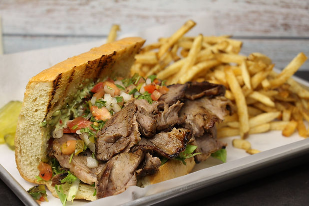 Plated Tri Tip Sandwich with pico di gallo, and a chimichurri sauce on bread. There are also french fries on the plate. This is a food item on the food truck menu.