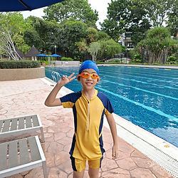Child in swim gear smiling by a swimming pool