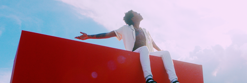 Singer Dwn2Earth singing while sitting on top of a red box