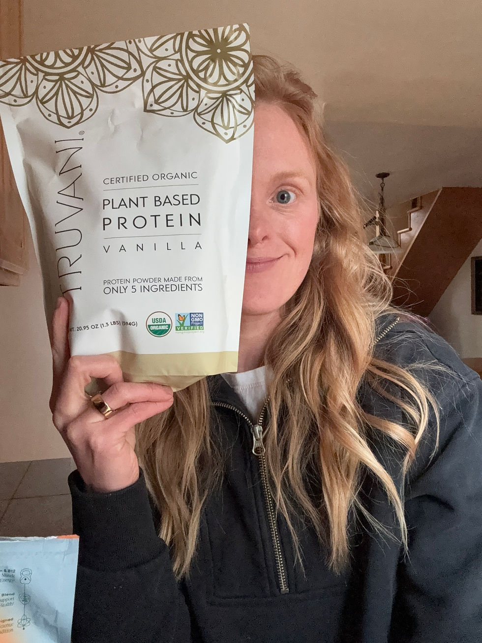 An image of Kate Costello, MS, CNS, LDN, holding a bag of Tuvani protein powder covering half of her face.
