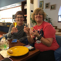 Two handbell ringers sitting together, toasting with champagne in flutes.