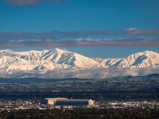 Snow-covered hills behind urban neighborhood rooftops in Tustin, California