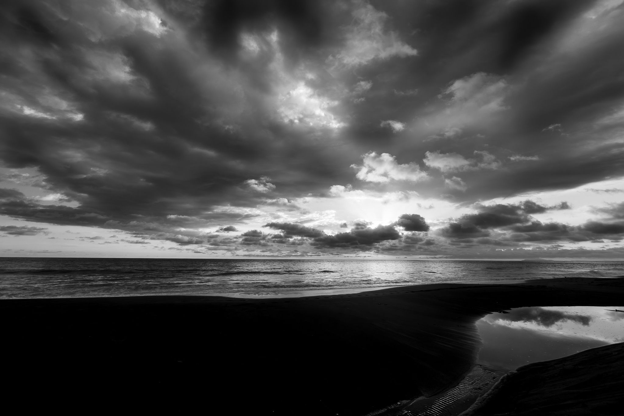 Dramatic black and white sunset over Playa Hermosa Costa Rica with storm clouds and volcanic black sand