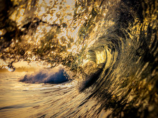 “Golden barrel wave glowing at sunset, sunlight streaming through the hollow curl of the wave — fine art ocean photography.”