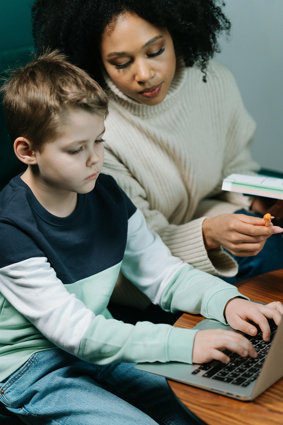 Woman helping young boy with homework on a laptop.