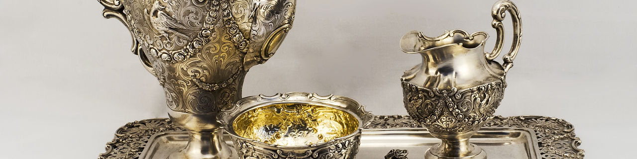 Silver coffee set. Silver sugar bowl, coffee pot, a jug of milk. They stand on a silver pl