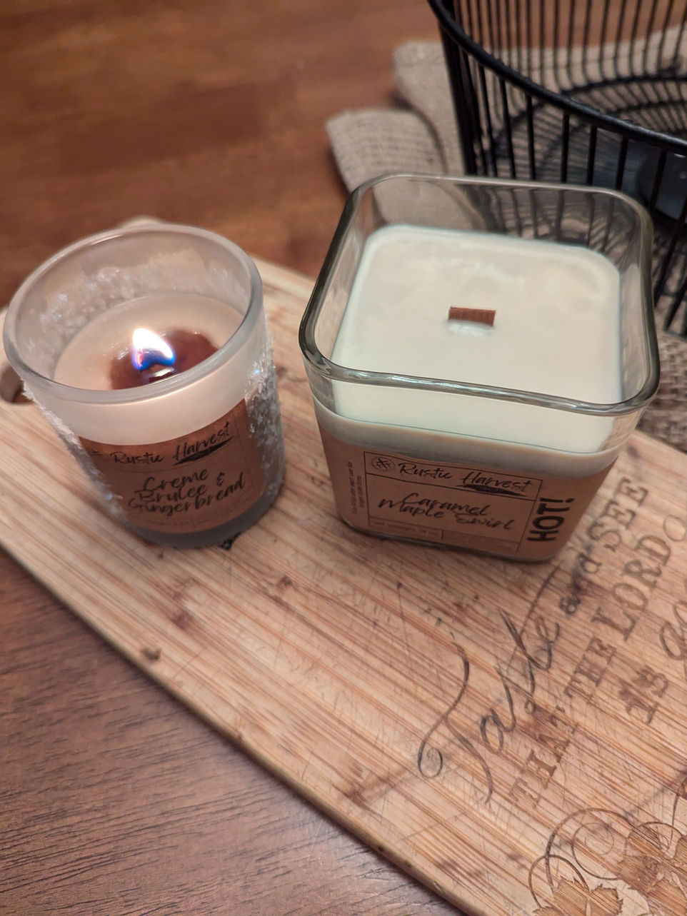 Hand-poured soy candles in rustic glass jars with wooden lids and crackling wood wicks, displayed on a wooden tray with cozy autumn décor.