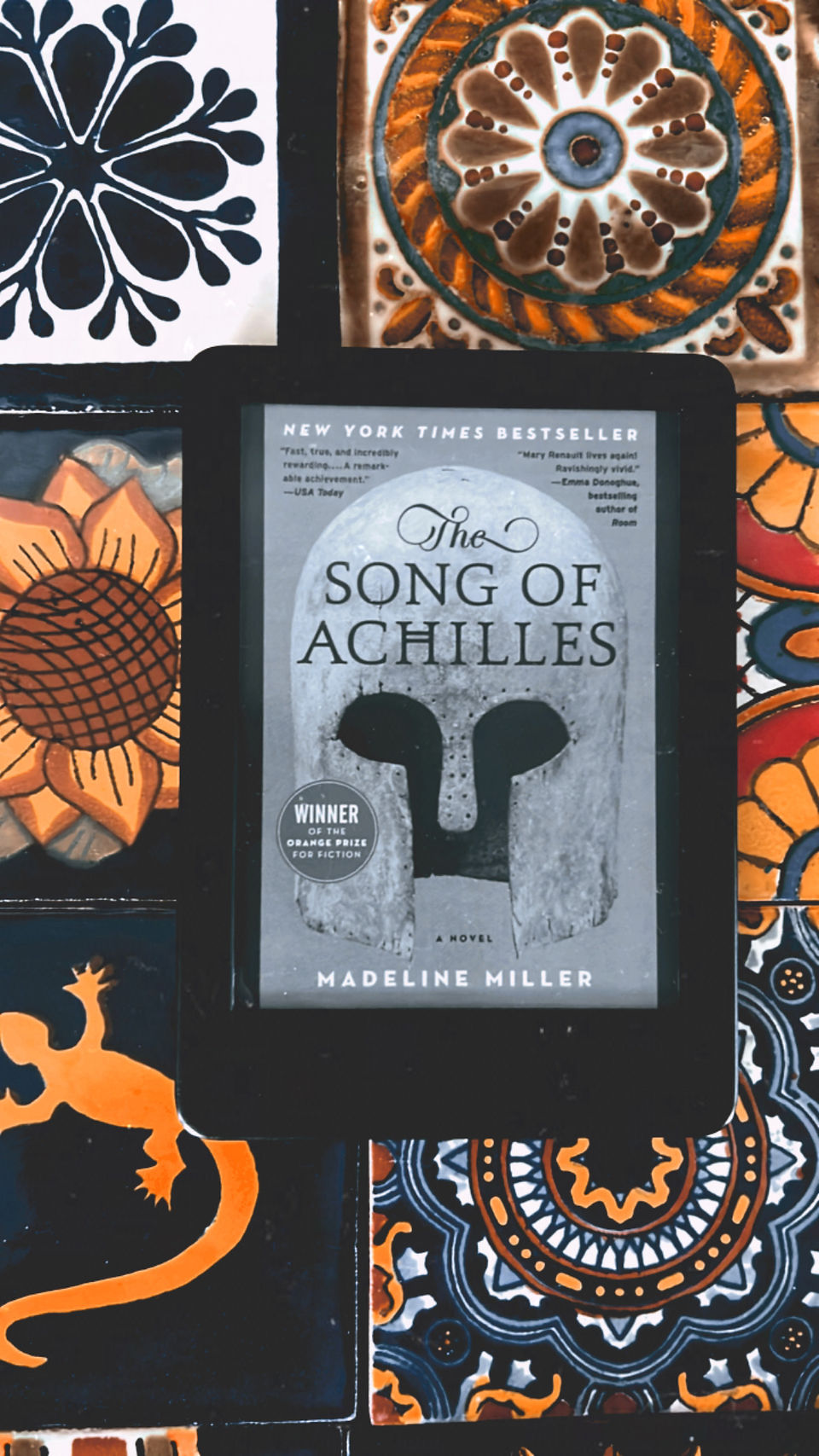"The Song of Achilles" book with colorful tiles as background.