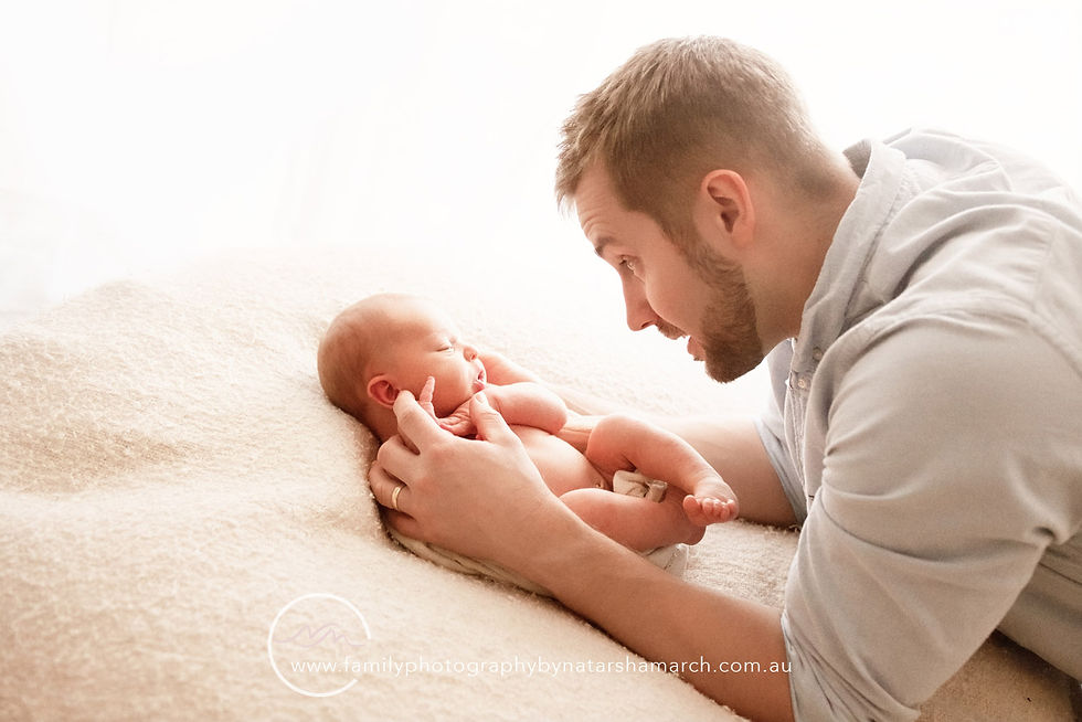 dad with cute expression looking down to newborn baby during photography session with Natarsha March in Brisbane