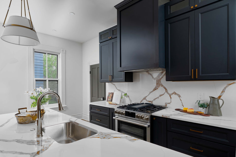 Contemporary kitchen with dark cabinets, veined countertops