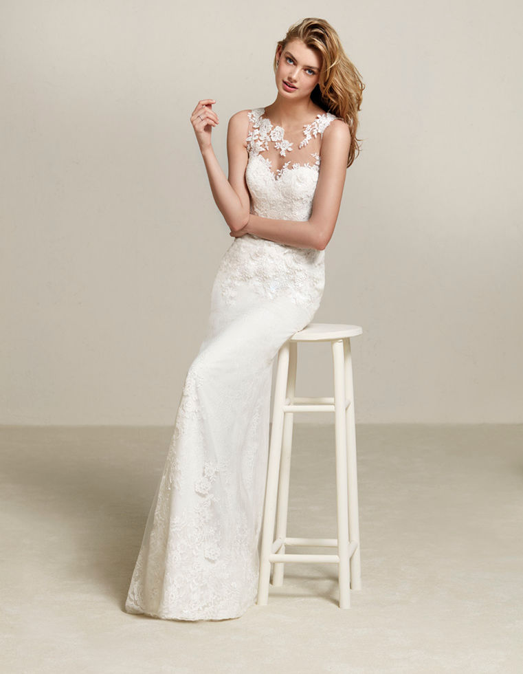 Modella indossa abito da sposa bianco, seduta su sgabello, Sposami Atelier.