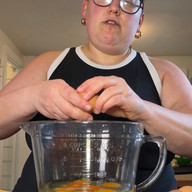 woman standing cracking eggs into a glass bowl