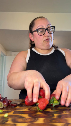 women placing strawberries on a wooden cutting board