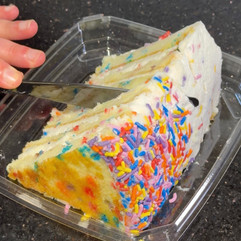 knife slicing into a piece of vanilla cake with sprinkles