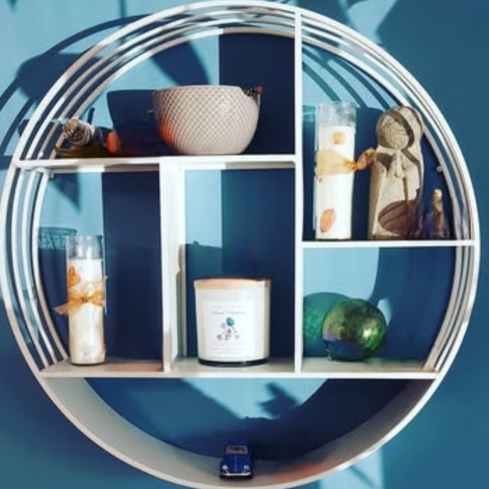Round white wall shelf with decorative objects highlighting visual detail and awareness of clutter in a changing home