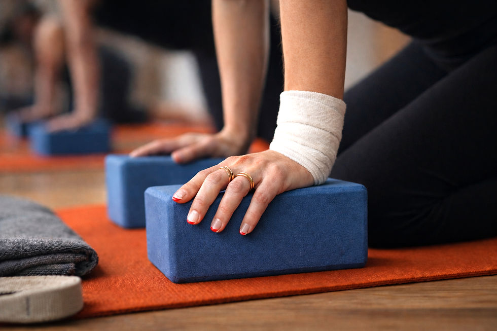 Close up of hands pressing into blue yoga blocks with a wrapped wrist during modified yoga practice at West Door Yoga in Bay Shore.