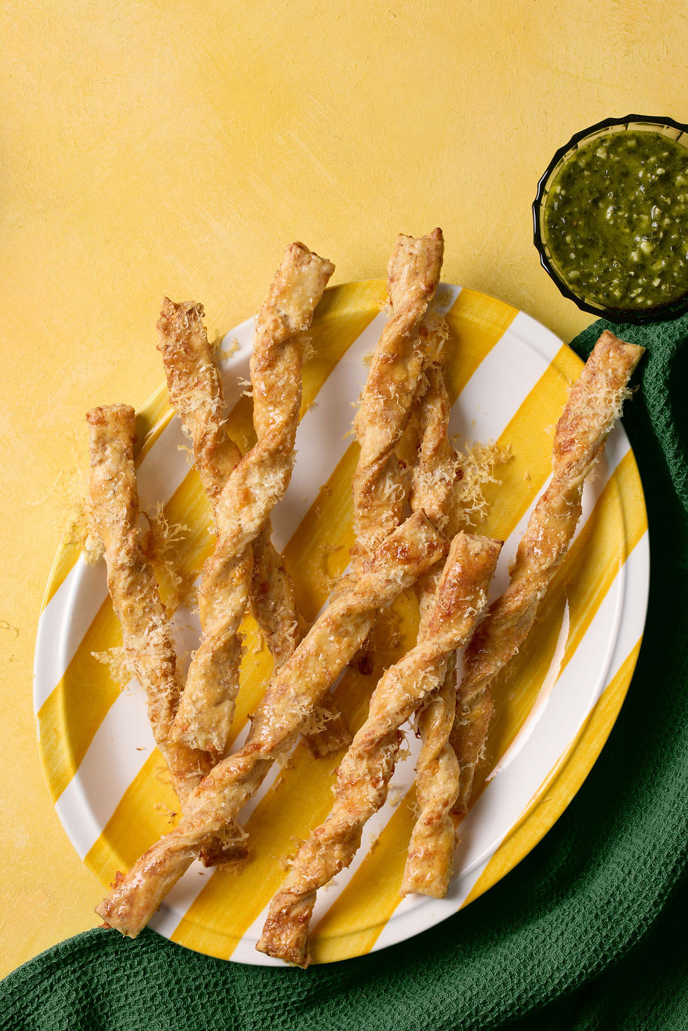 Golden savoury pastry twists with green dip, colourful editorial recipe photography by Richard Jarrett, London.