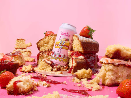 Creative commercial food photography featuring Yonder Victoria Sponge Cake beer surrounded by crumbling sponge cake and strawberry jam, photographed in London by Richard Jarrett.