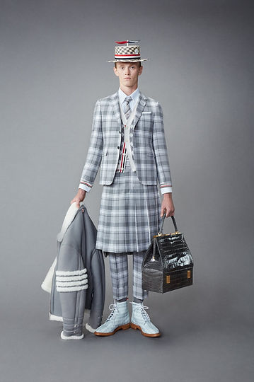 Model in Thom Browne’s Resort 2022 menswear collection wearing a surreal gray tailored suit with exaggerated proportions and a rabbit mask, blending conceptual design with traditional tailoring.