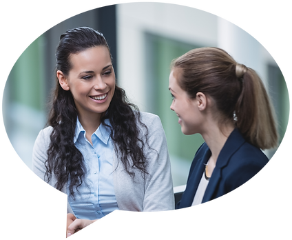 2 young female professionals smiling as they discuss feedback for one another at a fun FireStory Communication Academy training session hosted by their company in Nashville, TN.