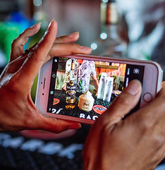 Human taking a photo at a catering event of a bartender putting together a drink.