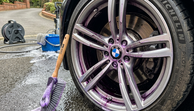 Close-up view of purple iron remover reacting on a silver wheel.