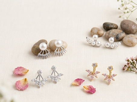 Vier Paar Ear Jackets auf Leinen: Oben links ein Pearl Ear Jacket mit silberner Stachelfassung, oben rechts ein Perlen-Reihen-Ear Jacket, unten links ein silbernes Zirkonia-BlĂĽten-Ear Jacket und unten rechts ein vergoldetes Zirkonia-Ear Jacket.
