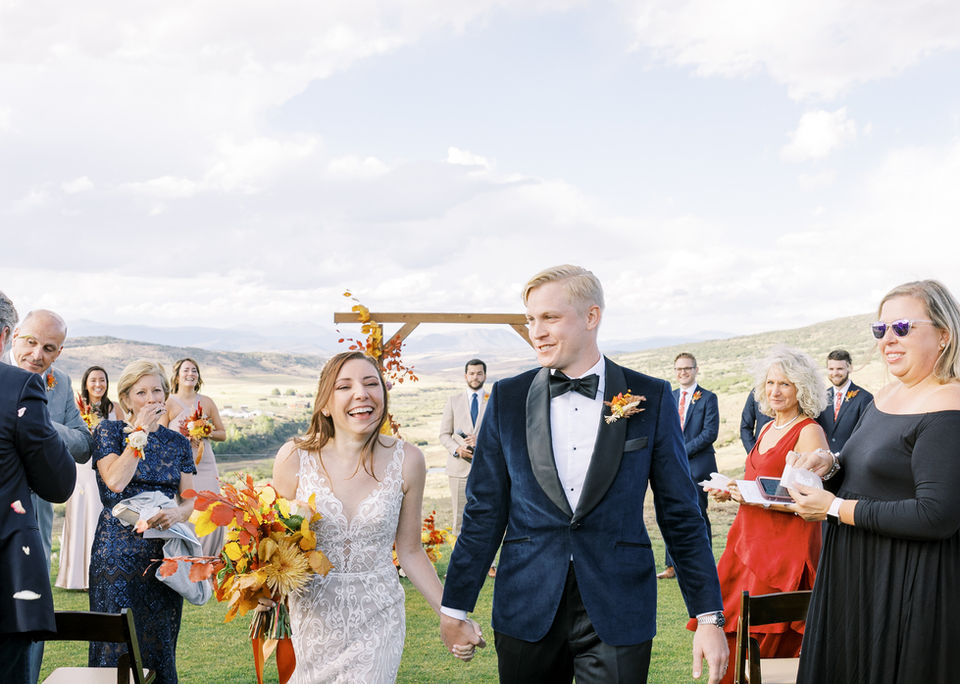 A man and wife walk down the isle after saying "I do" in the fall at a Colorado ranch wedding venue.