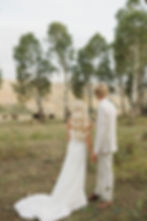 A bride and groom gazing at bison grazing beyond the aspen trees.