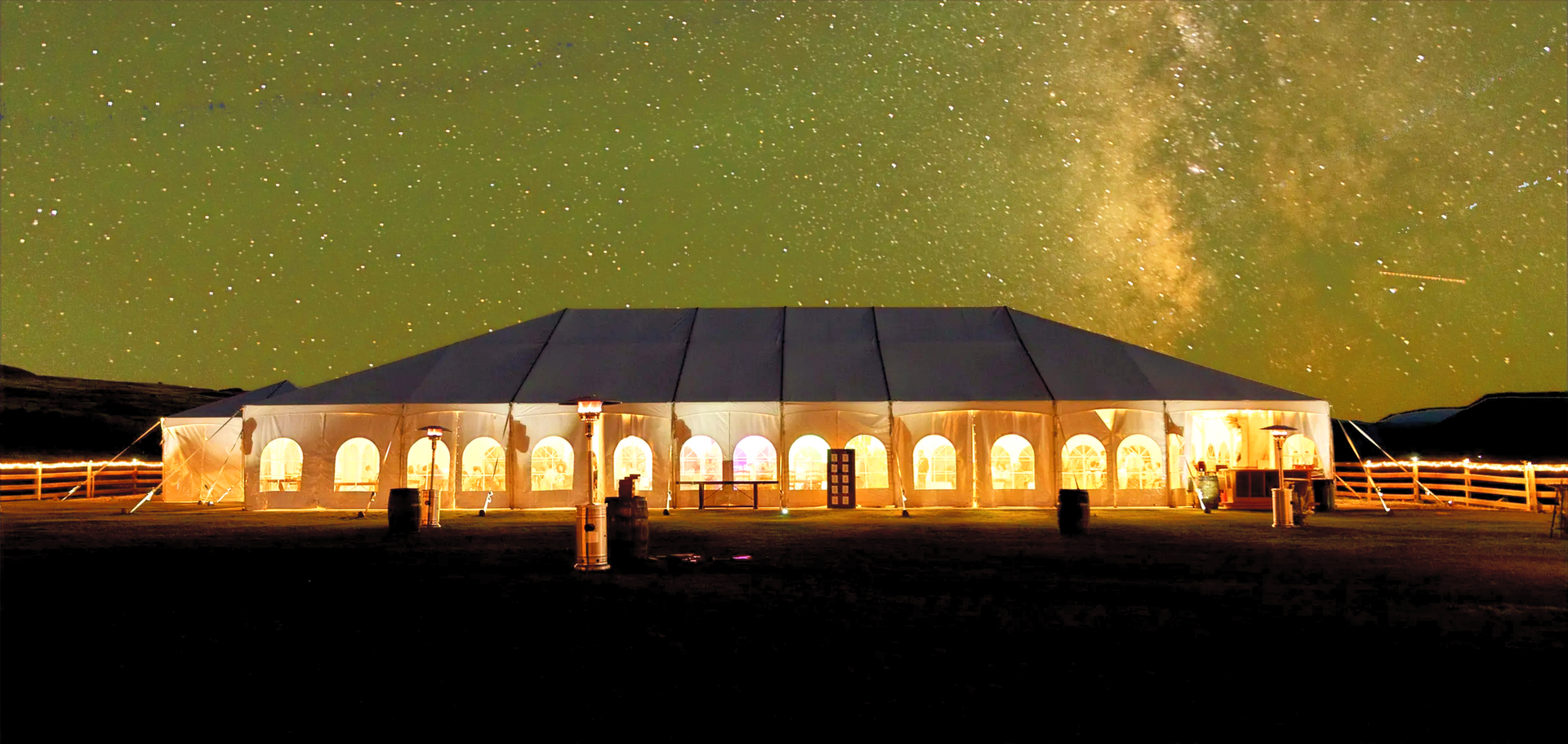 The wedding reception tent set in the foreground with the milky way shining above.