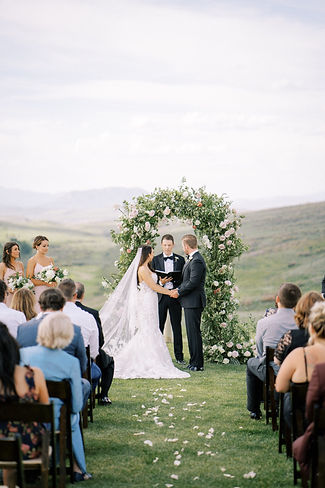 A bride and groom look eagerly to their officiant so they can share their first kiss at the Colorado Mountain View Lookout ceremony venue.