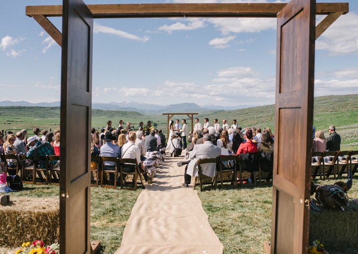 An outdoor Colorado wedding venue uses wooden French doors to highlight the brides entrance to her wedding. 
